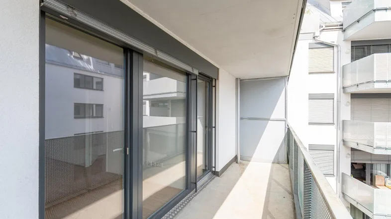 Heller Balkon mit Schiebetüren und Blick auf die umliegenden Gebäude der Stadt.