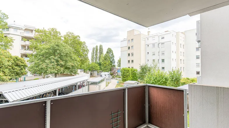 Balkon mit Blick auf umliegende Gebäude und Grünflächen in der Nachbarschaft.