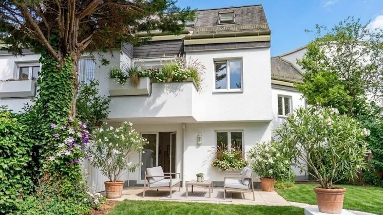 Charmantes Reihenhaus mit gepflegtem Garten, Terrasse und Balkon, umgeben von viel Grün.