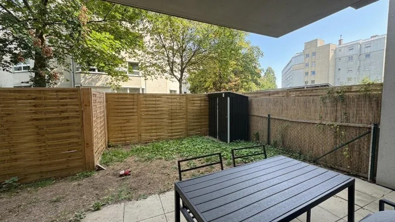 Kleiner privater Gartenbereich mit Terrasse, Gartenmöbeln und einem Geräteschuppen.