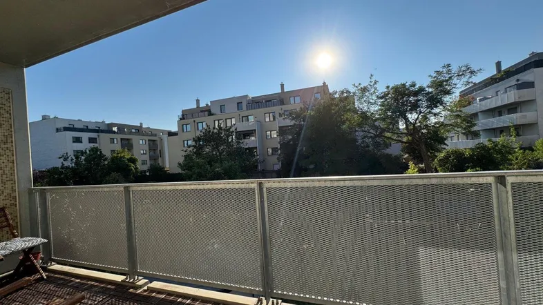 Heller Balkon mit Holzboden und Metallgeländer, bietet einen weiten Blick auf die umliegenden Gebäude.