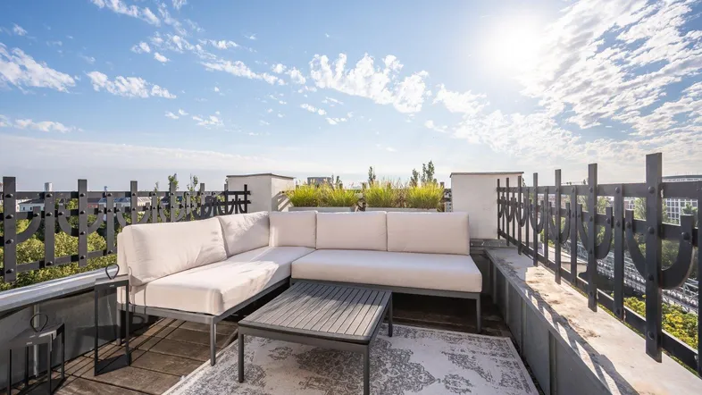 Geräumige Dachterrasse mit bequemen Loungemöbeln und weitem Blick unter blauem Himmel.