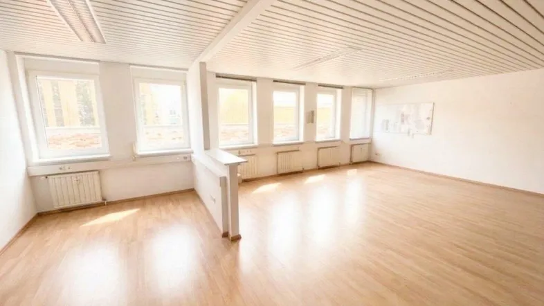 Heller, leerer Büroraum mit Holzfußboden, vielen Fenstern und einer Lamellendecke, in gutem Zustand.