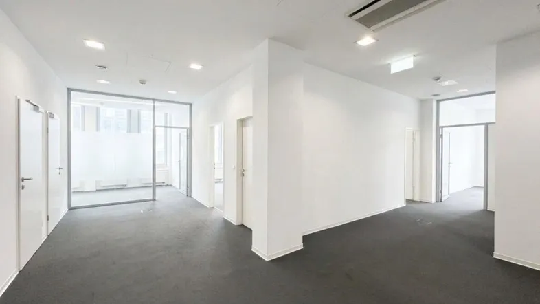 Moderner Bürobereich mit Teppichboden, Glastrennwänden und weißen Wänden.