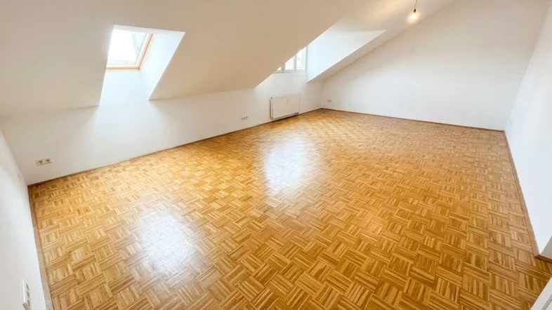Heller, geräumiger Dachbodenraum mit Parkettboden und Dachfenstern, ideal als vielseitiger Wohnbereich.