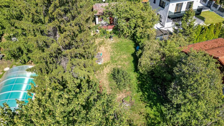 Luftaufnahme eines Grundstücks mit Garten, Baumbestand und einem überdachten Pool.