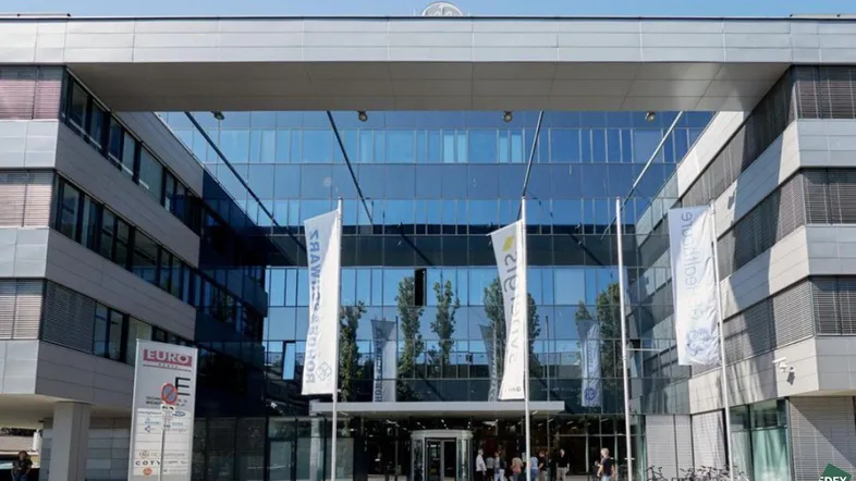 Moderne Bürogebäude-Fassade mit großer Glasfront und Haupteingangsbereich, der viel Tageslicht hereinlässt.