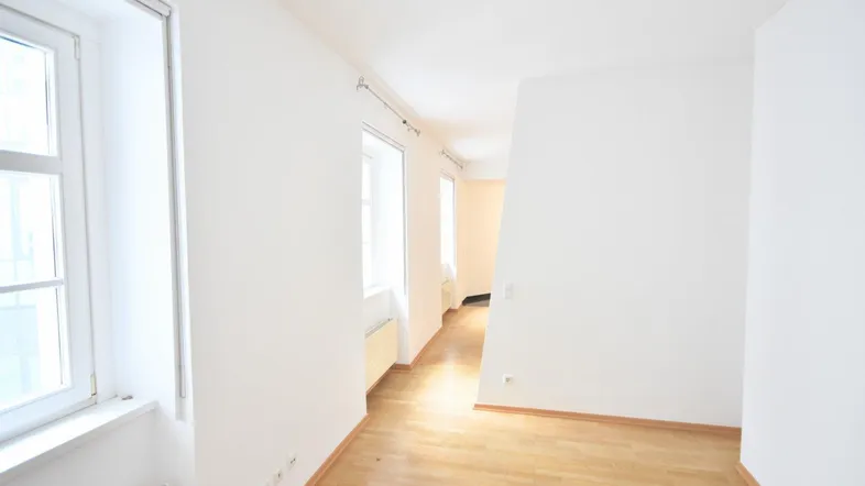Helles Zimmer mit Parkettboden und weißen Wänden, bereit zur individuellen Gestaltung.