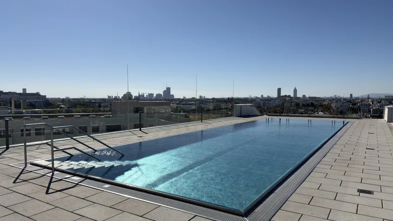 Moderner Infinity-Pool auf dem Dach mit weitem Blick über die Stadt.