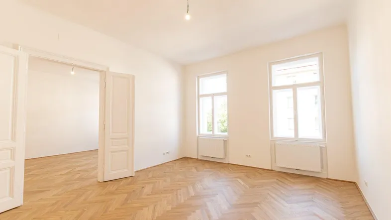 Helles Zimmer mit Fischgrätparkett und hohen Doppeltüren, bereit zur individuellen Gestaltung.