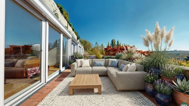 Geräumige Dachterrasse mit bequemen Loungemöbeln und üppiger Bepflanzung unter blauem Himmel.