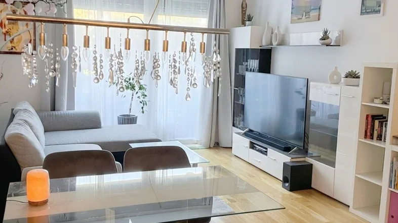Helles Wohn- und Esszimmer mit Parkettboden, modernem Sofa und Esstisch.