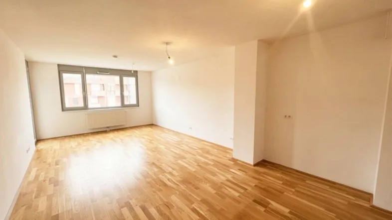 Helles, leeres Zimmer mit Parkettboden und großen Fenstern, bereit zur individuellen Gestaltung.