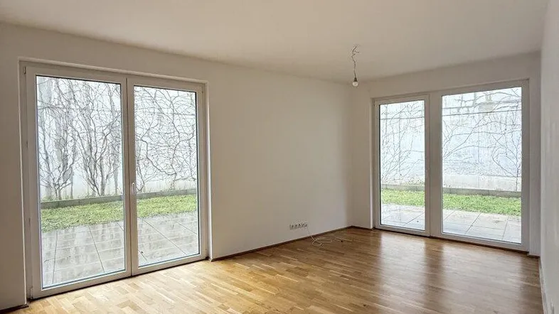 Helles Wohnzimmer mit Parkettboden und großen Fenstern zum Gartenbereich.