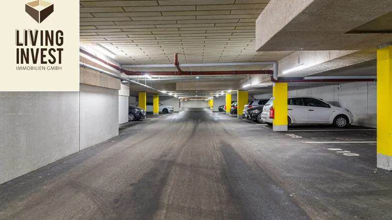 Tiefgarage mit mehreren Stellplätzen, Betonwänden und leuchtend gelben Säulen.