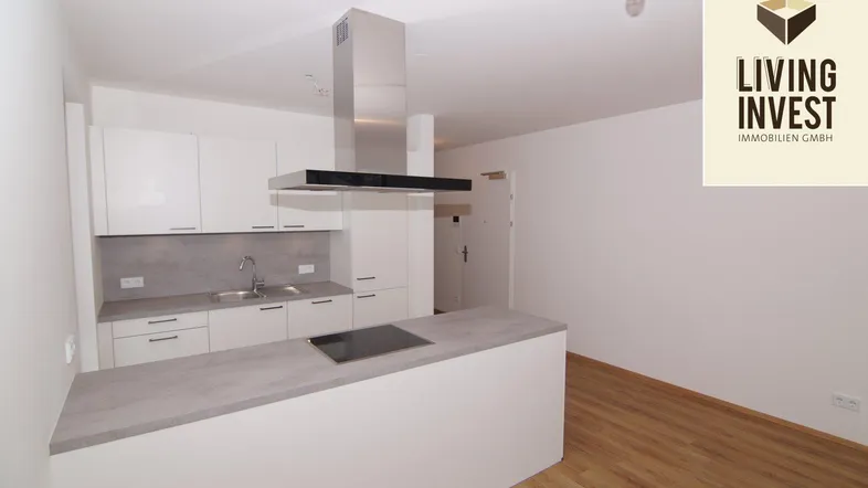 Moderne Einbauküche mit weißer Front, grauer Arbeitsplatte, Kochinsel und Laminatboden in neuwertigem Zustand.