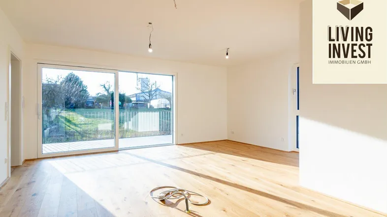Helles Wohnzimmer mit Holzboden, großen Schiebetüren und Zugang zum Gartenbereich.