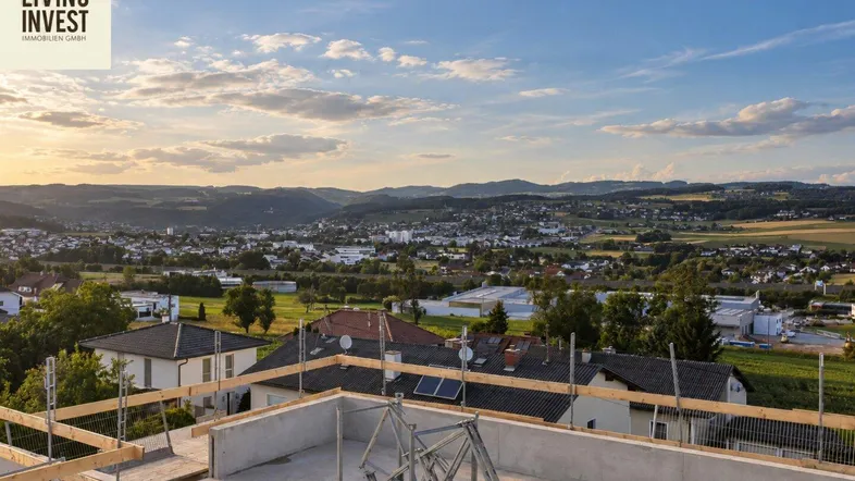 Luftaufnahme einer Baustelle mit weitem Blick über die umliegende Landschaft und Berge bei Sonnenuntergang.