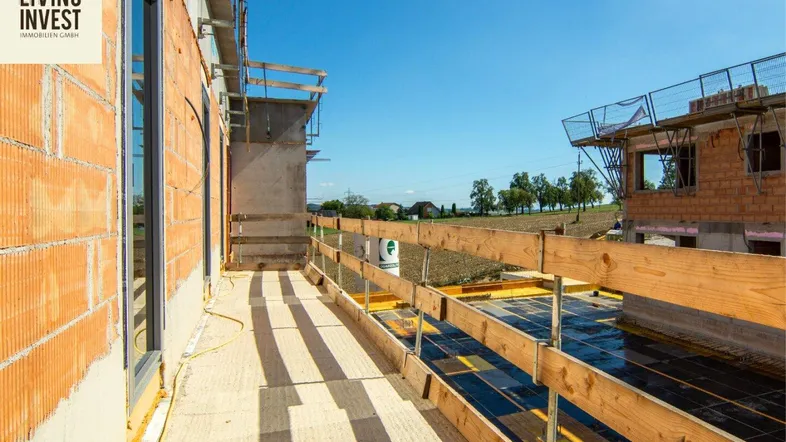 Balkon im Rohbau mit Holzsicherung und großen Fenstern, bietet einen weiten Blick auf die Umgebung.