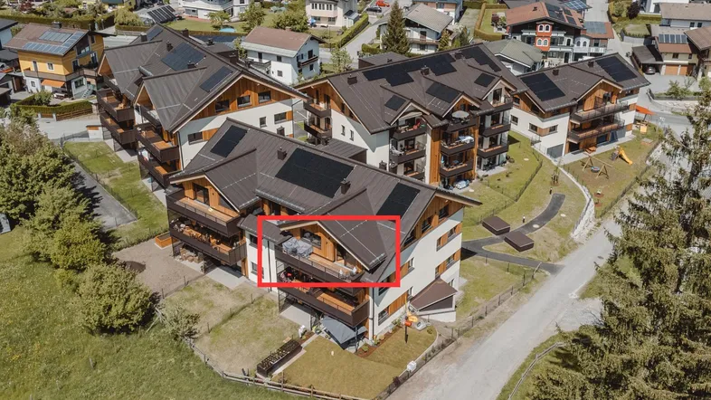 Luftaufnahme eines modernen Apartmentkomplexes mit Solaranlagen und Balkonen in ländlicher Umgebung.