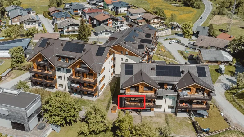 Luftaufnahme eines modernen Wohnkomplexes mit Balkonen und umliegender grüner Landschaft.