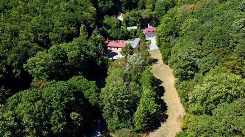 Luftaufnahme des Anwesens, eingebettet in dichte Wälder mit mehreren Gebäuden und Wegen.