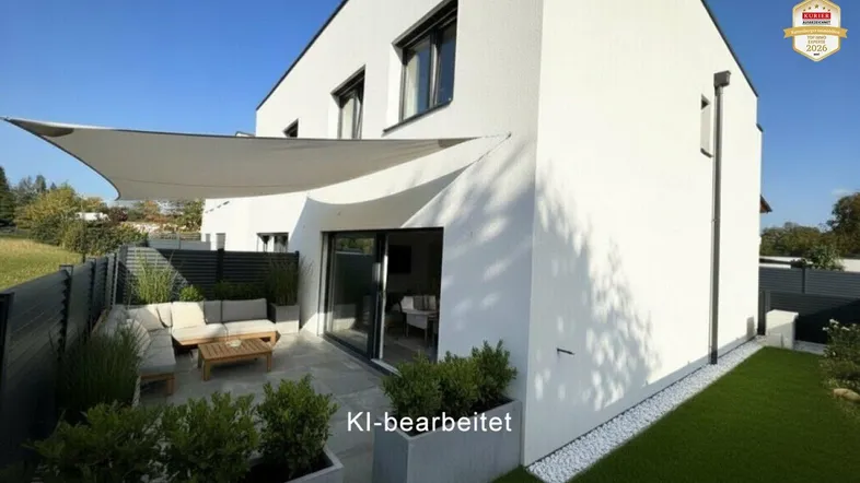Moderne Hausfassade mit großer, möblierter Terrasse und Sonnensegel, umgeben von Grünflächen.