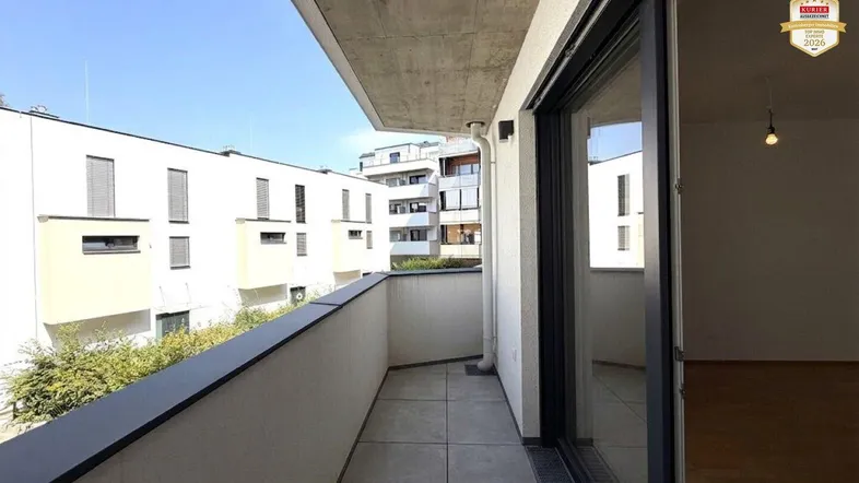 Geräumiger Balkon mit Fliesenboden und Blick auf die umliegenden Gebäude der Wohnanlage.