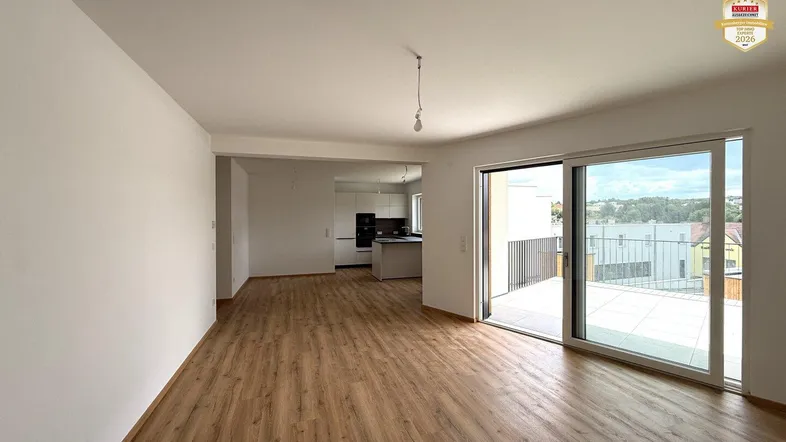 Heller offener Wohnbereich mit modernem Laminatboden und Zugang zu einer großen Terrasse.