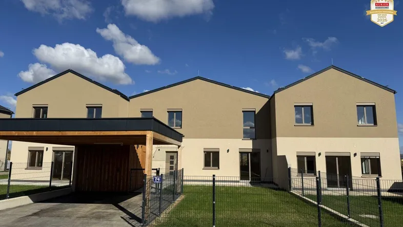 Reihenhäuser mit moderner Architektur, Carports und gepflegten Vorgärten unter blauem Himmel.
