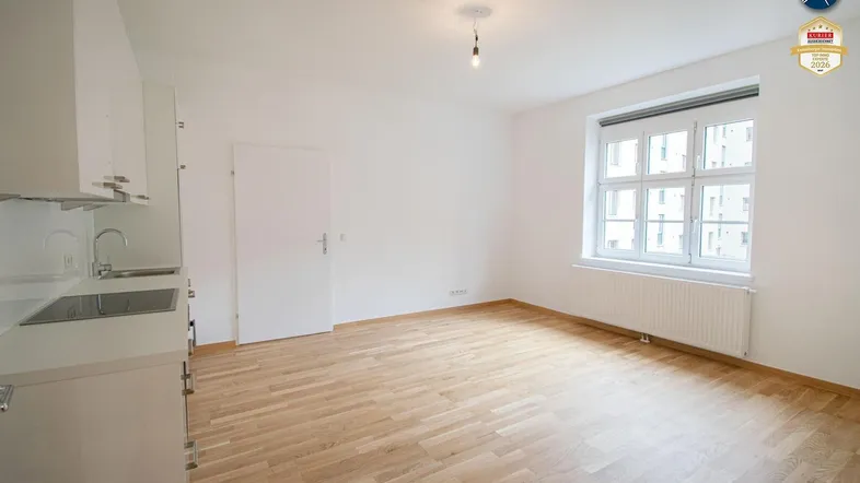 Heller Wohnraum mit Parkettboden und integrierter Küchenzeile, ideal für offenes Wohnen.