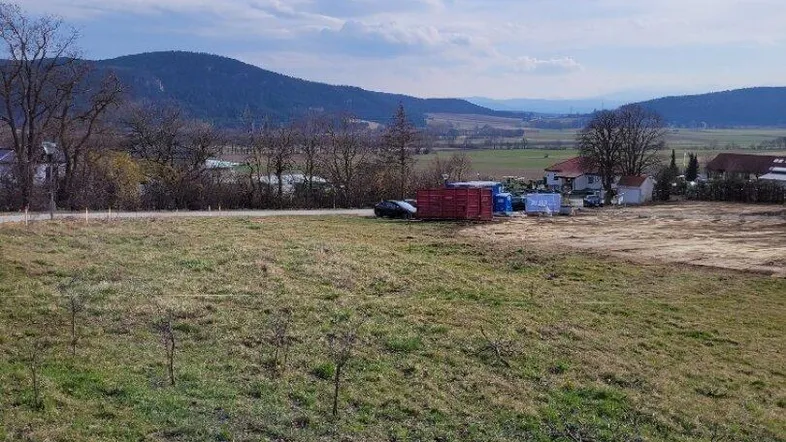 Weitläufige Grünfläche mit Blick auf die umliegende Landschaft und die fernen Berge unter blauem Himmel.