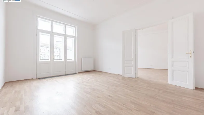 Helles, leeres Zimmer mit hohen Decken, großen Fenstern und hellem Parkettboden, bereit zur Einrichtung.