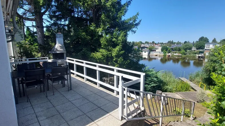 Geräumige Terrasse mit Essbereich, Grill und malerischem Blick auf den See und die umliegende Natur.