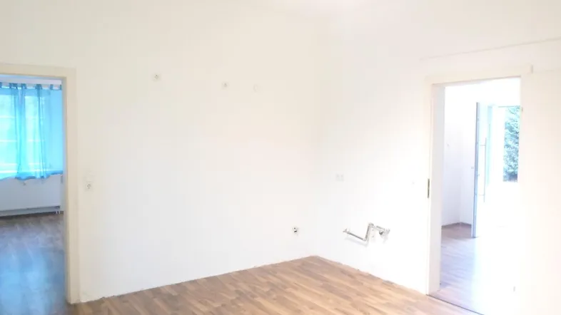 Helles Zimmer mit Laminatboden und Zugang zu einem weiteren Raum.