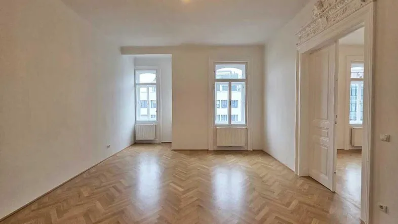 Helles Wohnzimmer mit Fischgrätparkett und hohen Flügeltüren, bereit für die individuelle Gestaltung.