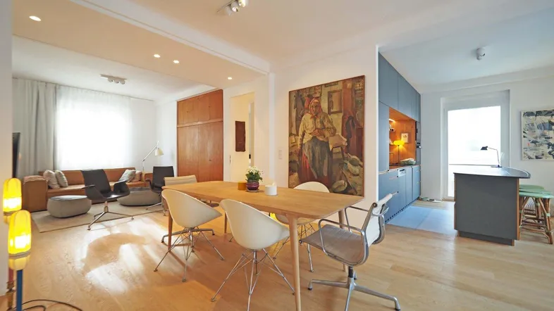 Helles Wohn- und Esszimmer mit Holzboden, modernem Esstisch und gemütlicher Sitzecke.
