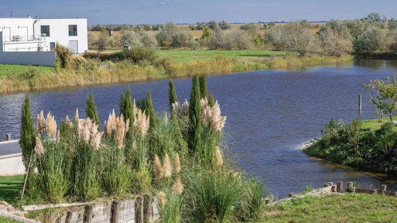 Moderne Architektur am Wasser mit üppiger Vegetation und weitem Blick auf die Landschaft.
