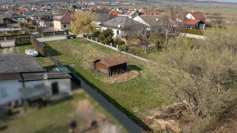Luftaufnahme eines unbebauten Grundstücks mit kleinem Schuppen und Blick auf die umliegende Wohnsiedlung.