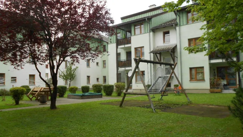 Wohngebäude mit gepflegter Grünanlage, Kinderspielplatz und Balkonen in einer ruhigen Umgebung.