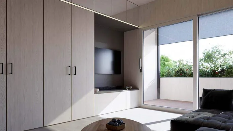 Modernes Wohnzimmer mit integrierten Schränken, TV-Bereich und Zugang zur Terrasse.