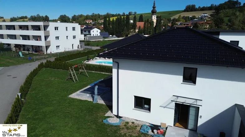 Luftaufnahme eines modernen Hauses mit Pool, Garten und Blick auf die umliegende Landschaft.