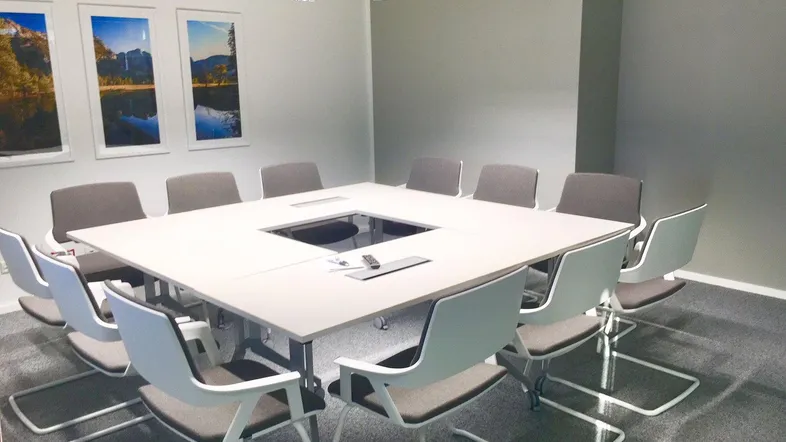 Moderner Konferenzraum mit großem Tisch, bequemen Stühlen und integrierter Technik für effiziente Besprechungen.
