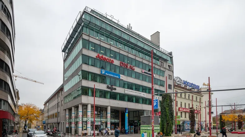 Modernes Bürogebäude mit Glasfassade und mehreren Etagen in urbaner Umgebung.