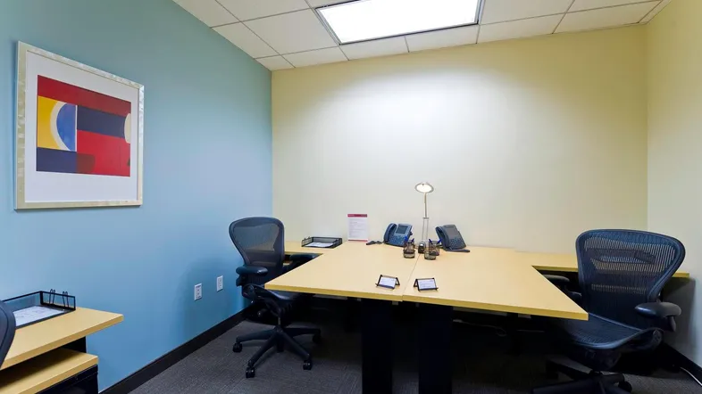 Büro mit zwei Arbeitsplätzen, blauer Akzentwand und Teppichboden, ideal für kleine Teams.