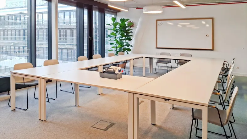 Moderner Konferenzraum mit U-förmigem Tisch, großen Fenstern und viel Tageslicht für Besprechungen.