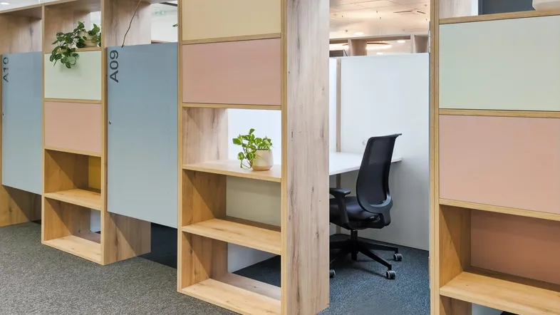 Moderner Bürobereich mit individuellen Arbeitsplätzen, farbigen Trennwänden und Pflanzen in mint-Zustand.