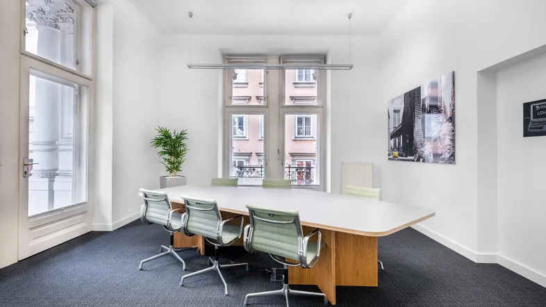 Heller Konferenzraum mit großem Holztisch, modernen Stühlen und Blick auf die Stadt.