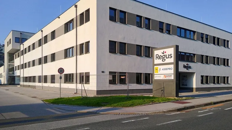 Modernes Bürogebäude mit weißer Fassade und großen Fenstern, gut sichtbar von der Straße.