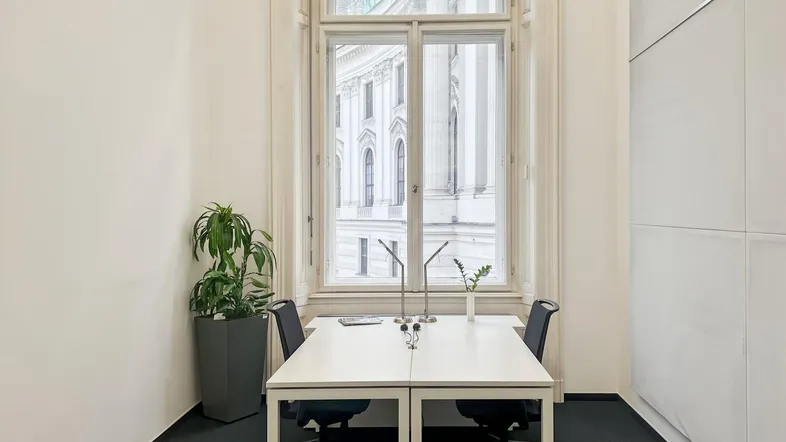 Heller Büroraum mit großem Bogenfenster, das viel Tageslicht hereinlässt und eine angenehme Arbeitsatmosphäre schafft.
